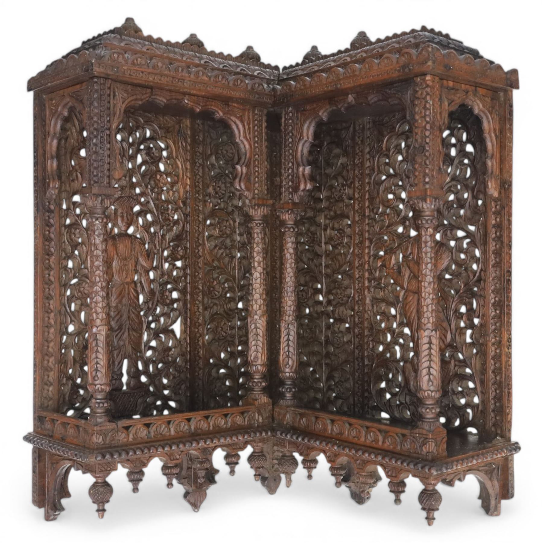 20th century Indian carved hardwood corner shelf, the tiered pagoda form with pierced and carved foliate panels centred by figural carving, supported by turned and carved columns, with shaped brackets and pendant finials