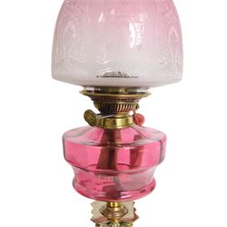 Victorian brass oil lamp, the Corinthian column supporting a cranberry glass burner and opaque etched cranberry glass shade and clear glass chimney, overall H77cm