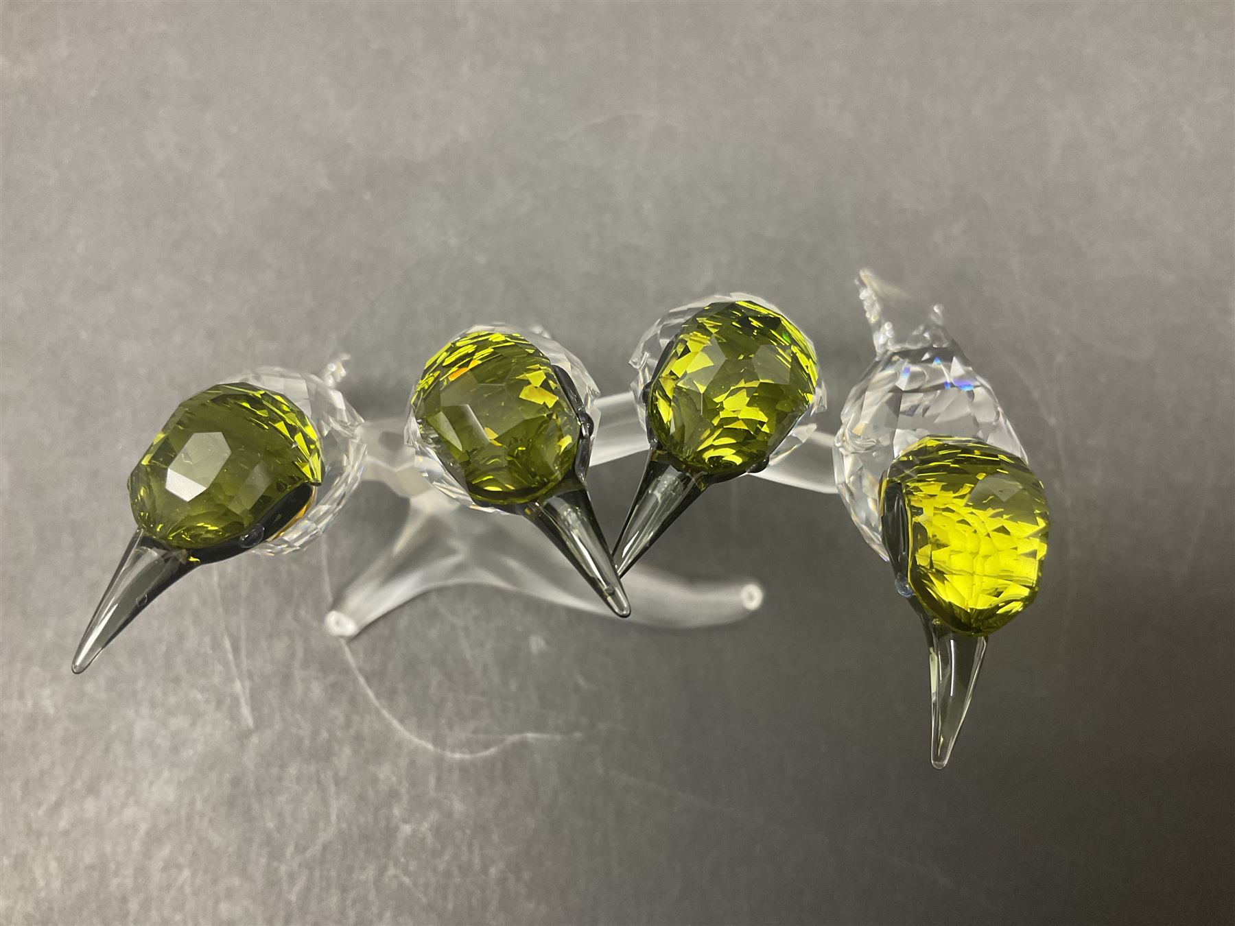 Four Swarovski Crystal bird figures, comprising Cockatoo, pair of Hoopoes on a branch, four Lovebirds on a branch and four Hummingbirds on a branch, largest H10cm