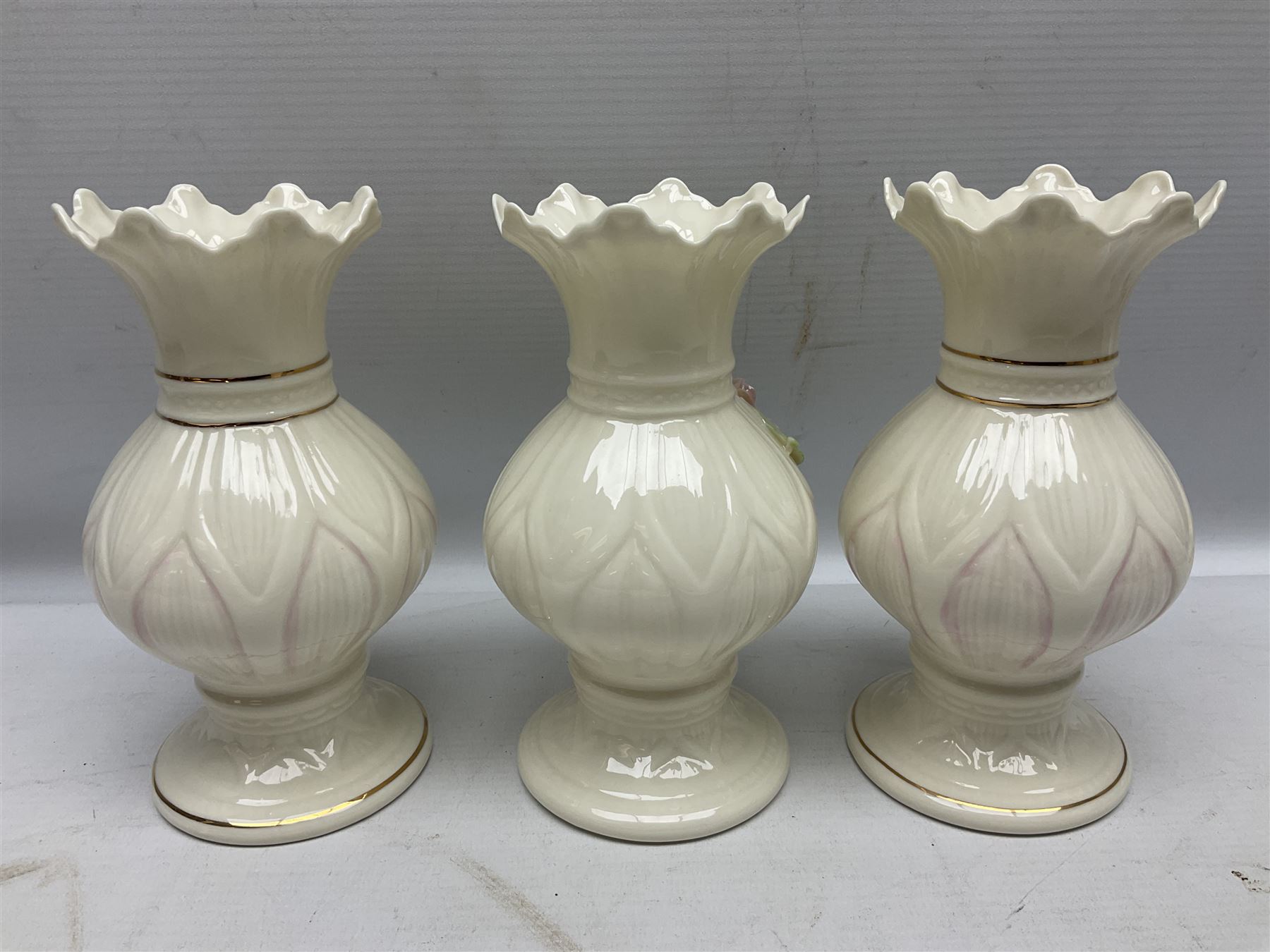 Five late 19th/early 20th century and later Belleek vases, comprising pair of Lotus Blossom examples, shamrock tree trunk vase, twin handled shamrock vase and a baluster form vase decorated with applied roses, all with printed marks beneath, tallest H16cm