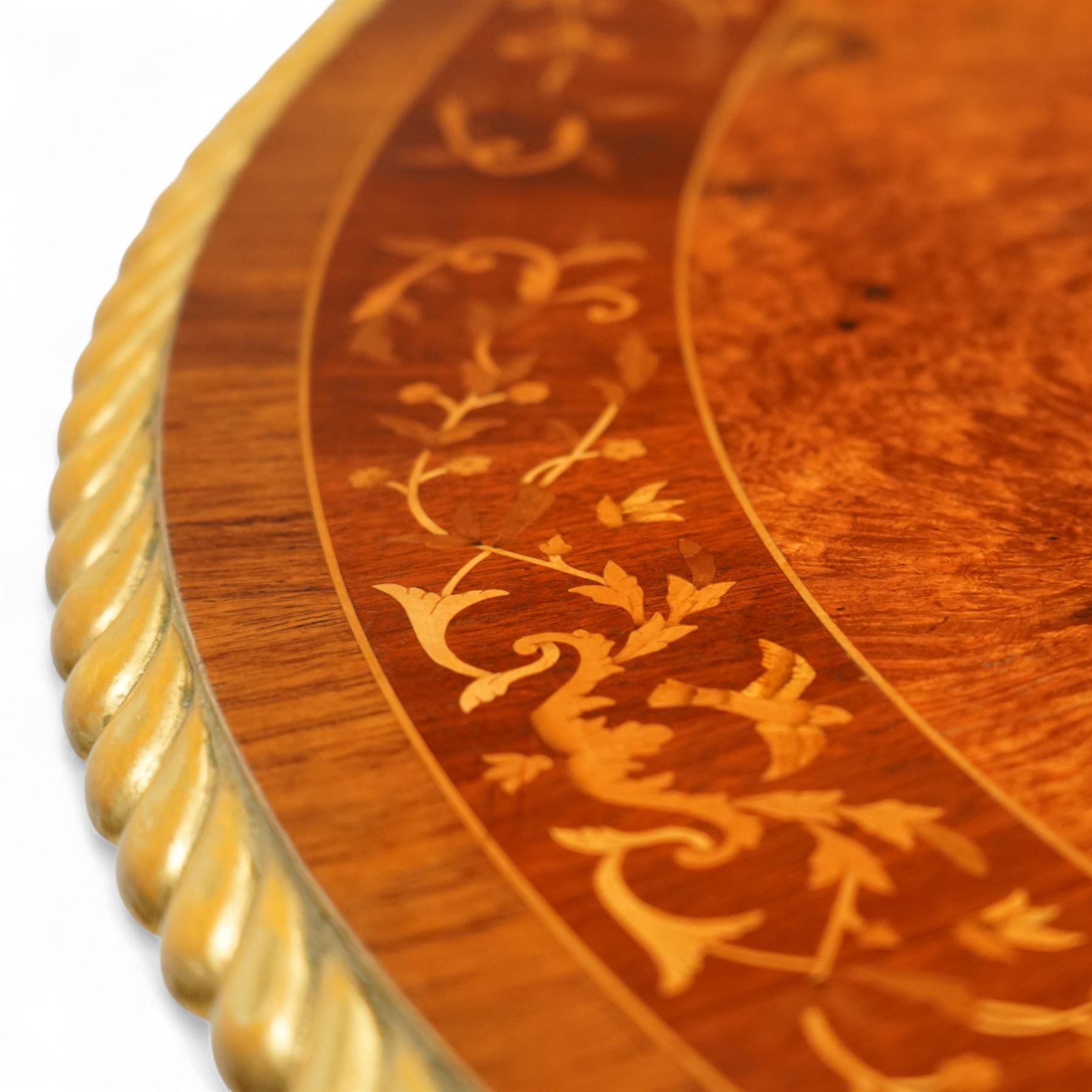 Arthur Brett & Sons - late 20th century twin pedestal dining table in the Second Empire style, the oval Amboyna burl veneered top, bordered with tulipwood crossbanding and delicate floral marquetry inlay, and rosewood crossbanded outer border within gilt gadrooned edge, over two mahogany triform pedestal bases with rosewood crossbanding and decorated with neoclassical marquetry of tied ribbons, leafy sprays, and scrolling acanthus decoration, raised on carved and gilded lion paw terminals on plinth bases, underside with maker's label