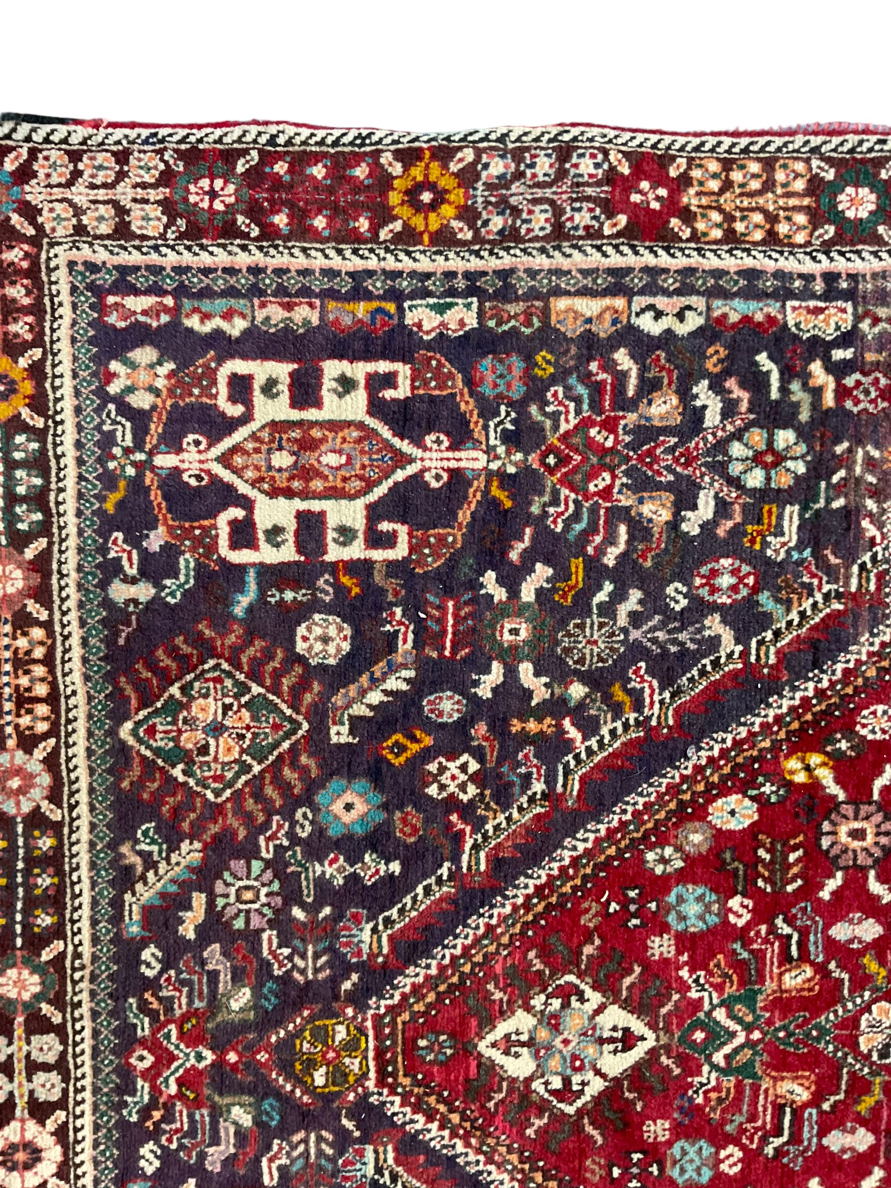 Persian Heriz crimson ground rug, field with large central lozenge surrounded by stylised plant motifs in a mauve background, guarded border with repeating foliage