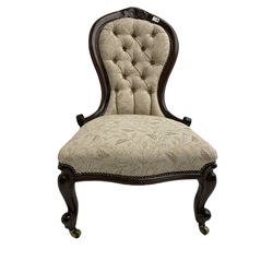 Victorian walnut spoon back nursing chair, the cresting rail carved with flower head and scrolls, upholstered in buttoned foliate patterned fabric, on cabriole front supports, brass castors