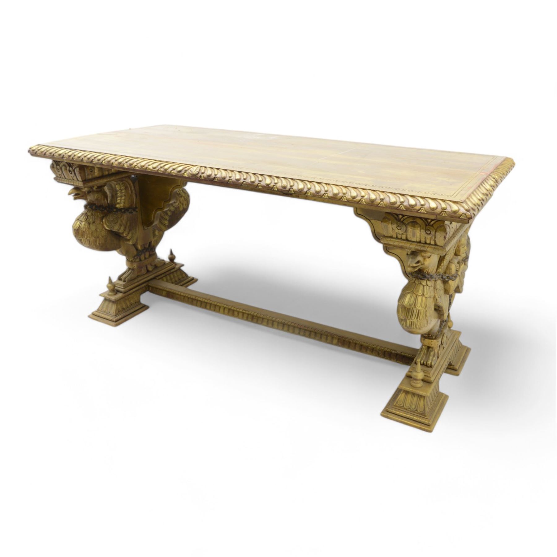 19th century Renaissance Revival carved and giltwood centre table, the rectangular top with gadrooned edge and carved frieze of repeating arched motifs with stylised scrolls, supported by a pair of carved winged griffin supports restrained by a central chained figure, on stepped rectangular bases united by carved stretcher