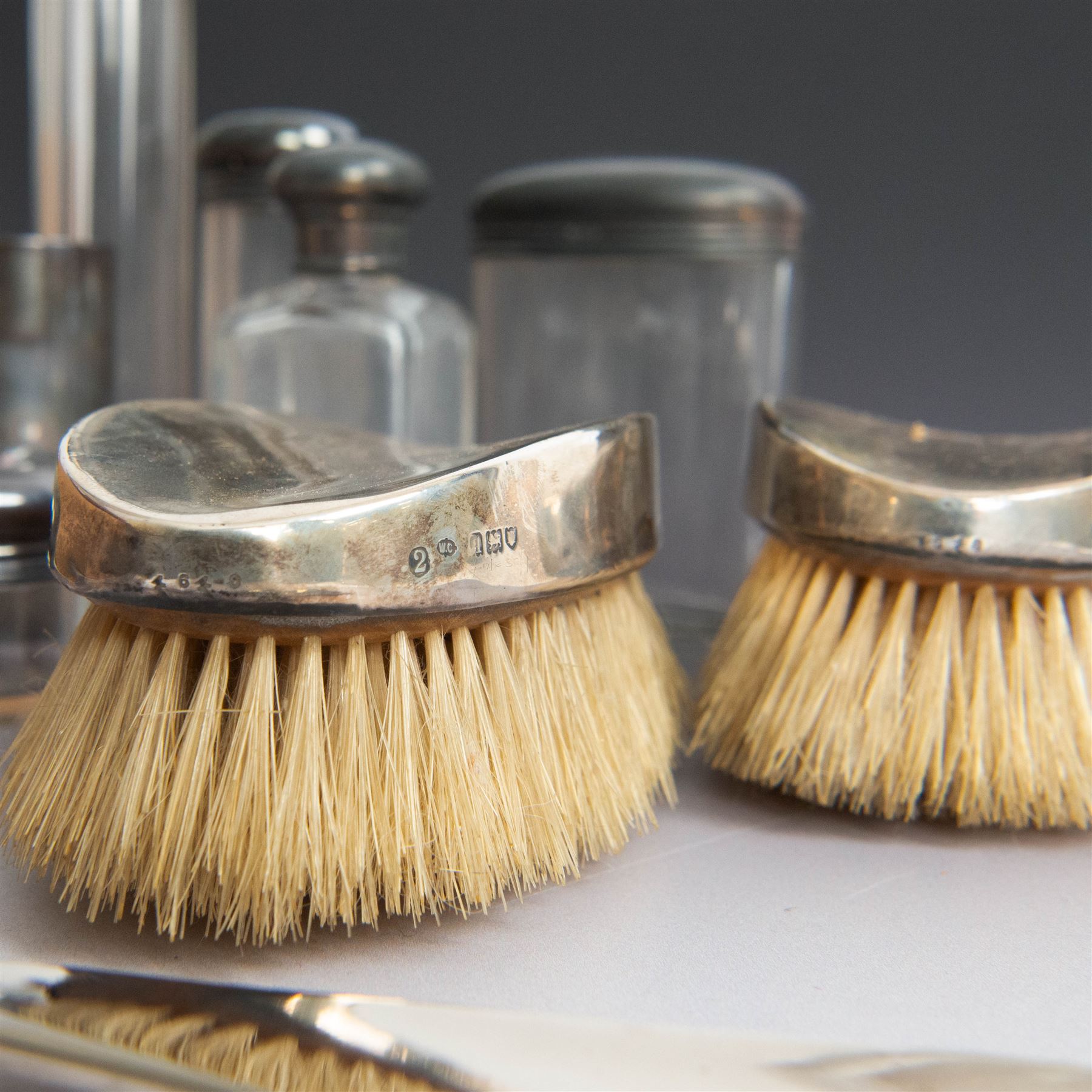 1920s gentleman's travelling case by Mappin & Webb Ltd, tan leather impressed with initials NAO, opening to reveal a compartmentalised interior containing silver mounted dressing table items, including a pair of silver mounted brushes, engraved NAO AMA 1918, hallmarked William Comyns, London 1911, five faceted glass jars and bottles with silver lids and a silver shaving brush holder, all hallmarked Mappin & Webb Ltd, London 1922, tan leather box containing razor, silver plated shoe horn, scissors and bevelled edge shaving mirror with easel support