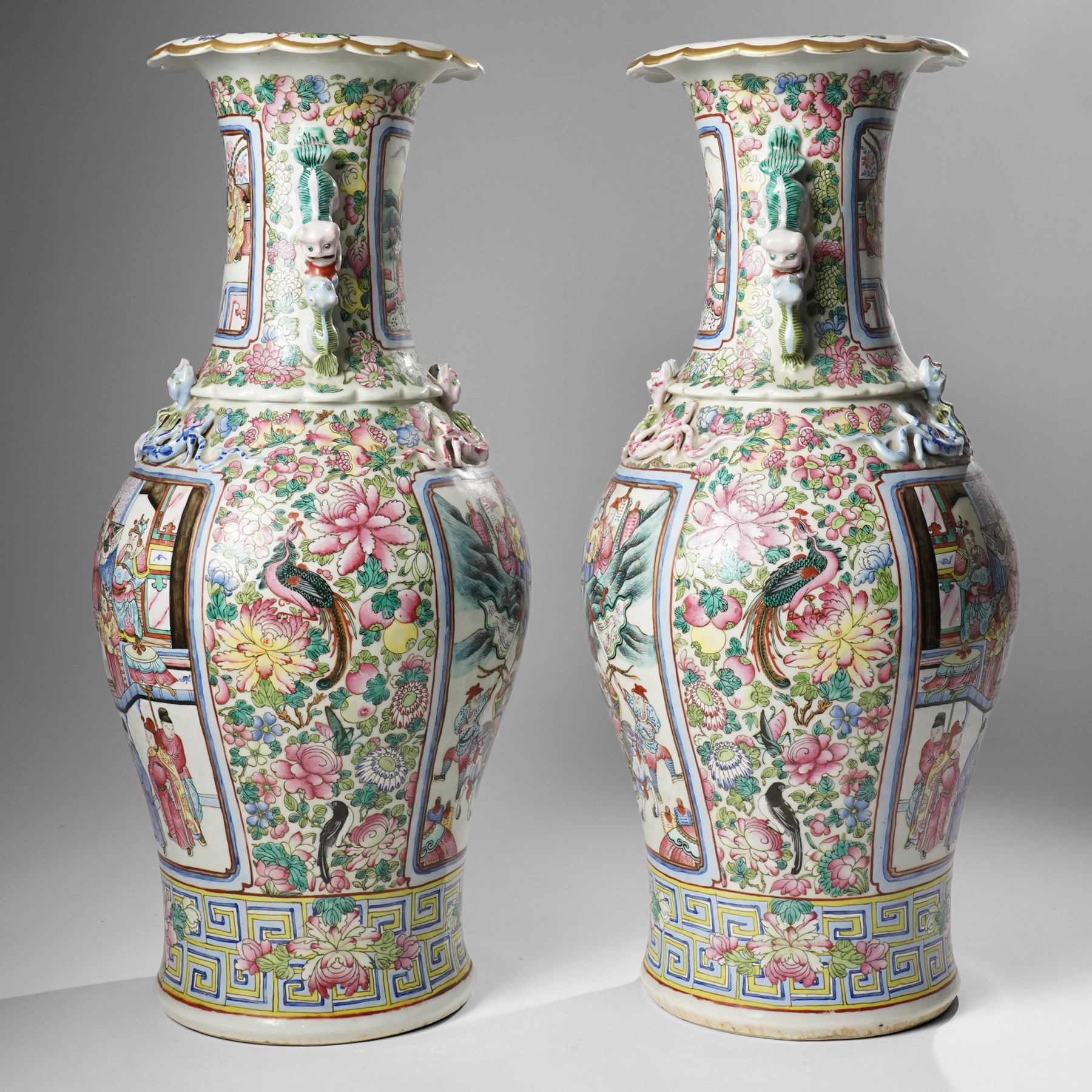 Large pair of 19th century Cantonese famille rose vases, each painted with various courtly scenes, including a display of warriors fighting on horseback before an official and his attendants, double Buddhist lion handles and applied at the shoulders with chilong, the lower band painted with Greek key motif, H58cm (2)