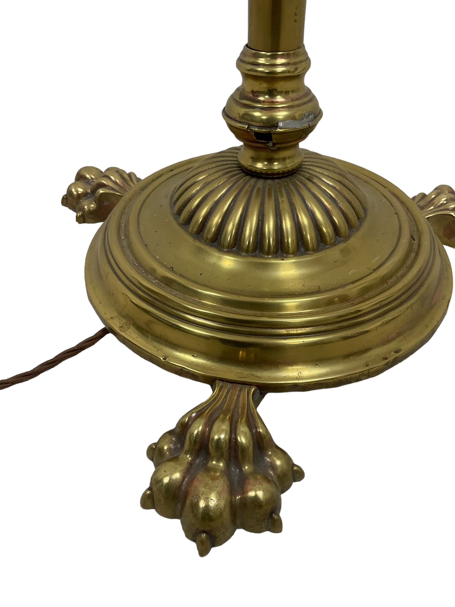 Edwardian brass plated copper standard lamp, telescopic stem on lobe moulded circular base with three projecting paw feet, with cream shade