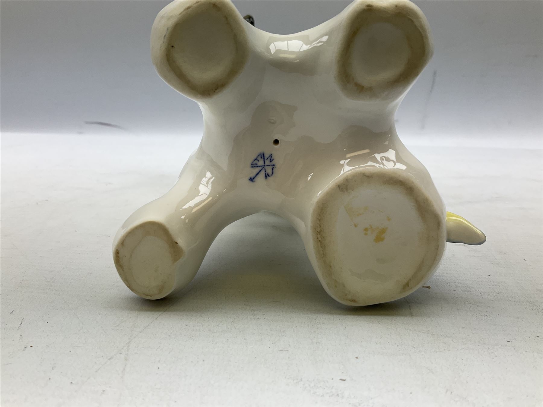 Karl Ens porcelain figure of a parrot, modelled with yellow breast, blue back and wings and green tail, perched upon on a blossoming branch, with blue printed factory mark beneath, H24.5cm