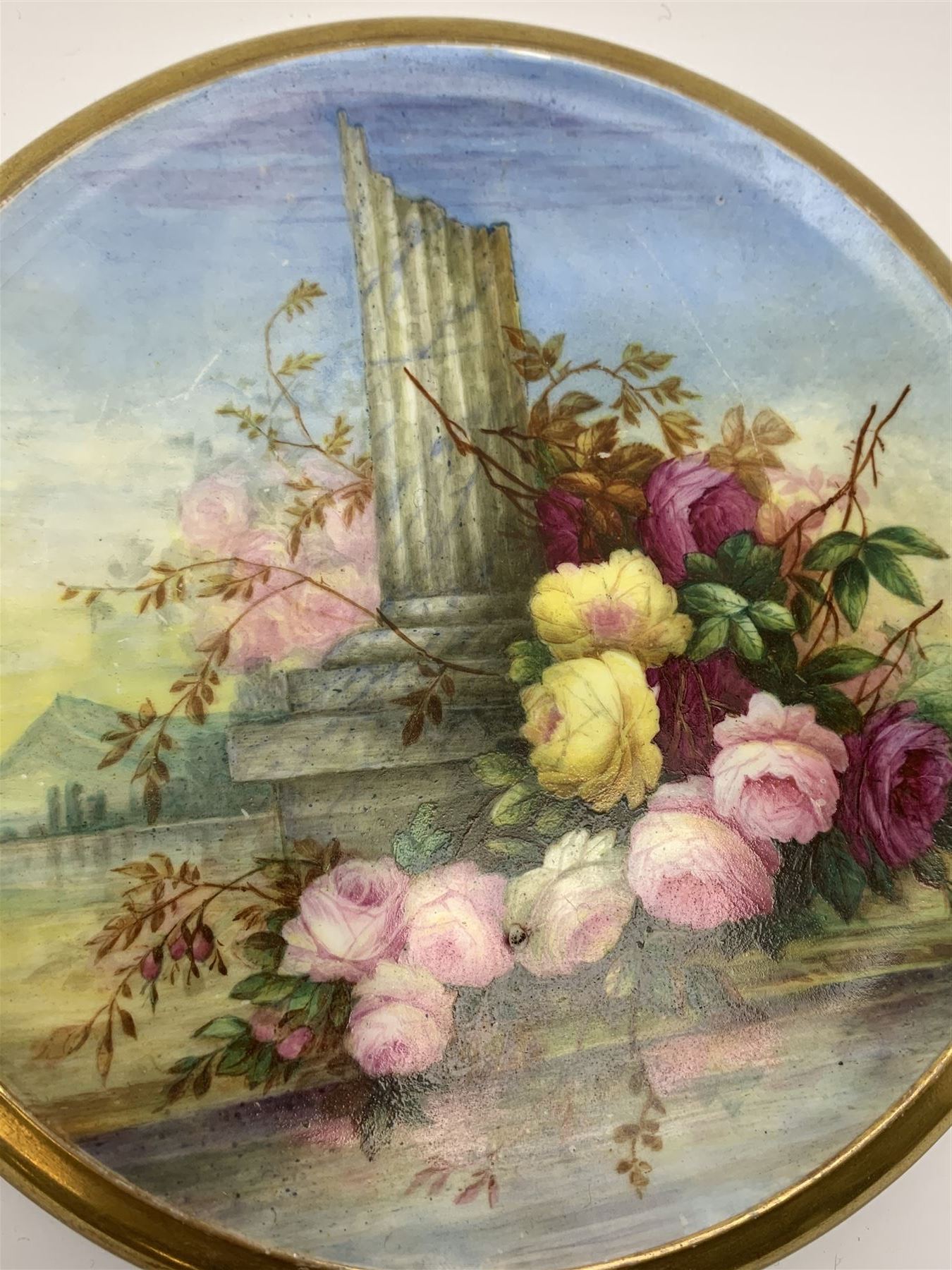 19th century porcelain stand, of circular form, in the Derby style, hand painted with a ruinous column and roses against a landscape background, within a gilt border, D7cm