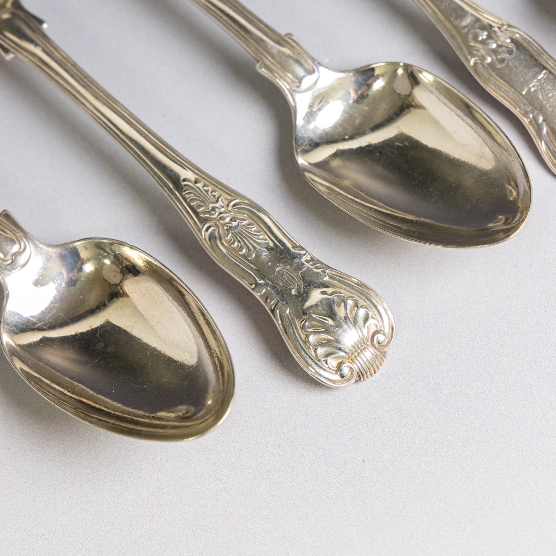 Seven silver Kings/Queens pattern dessert spoons, including George III Irish silver pair with engraved griffin crests, hallmarked Dublin 1818, maker's mark SI and five with varying dates and makers, all hallmarked 