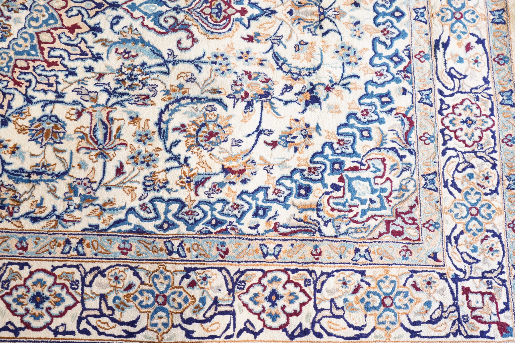 Persian Nain ivory ground rug, the busy oval field profusely decorated with scrolling foliate decoration and palmettes in citrine and indigo tones, the central medallion with matching spandrels, the multiple guard bands with repeating stylised quatrefoil motifs and trailing scrolling foliage and flowerheads