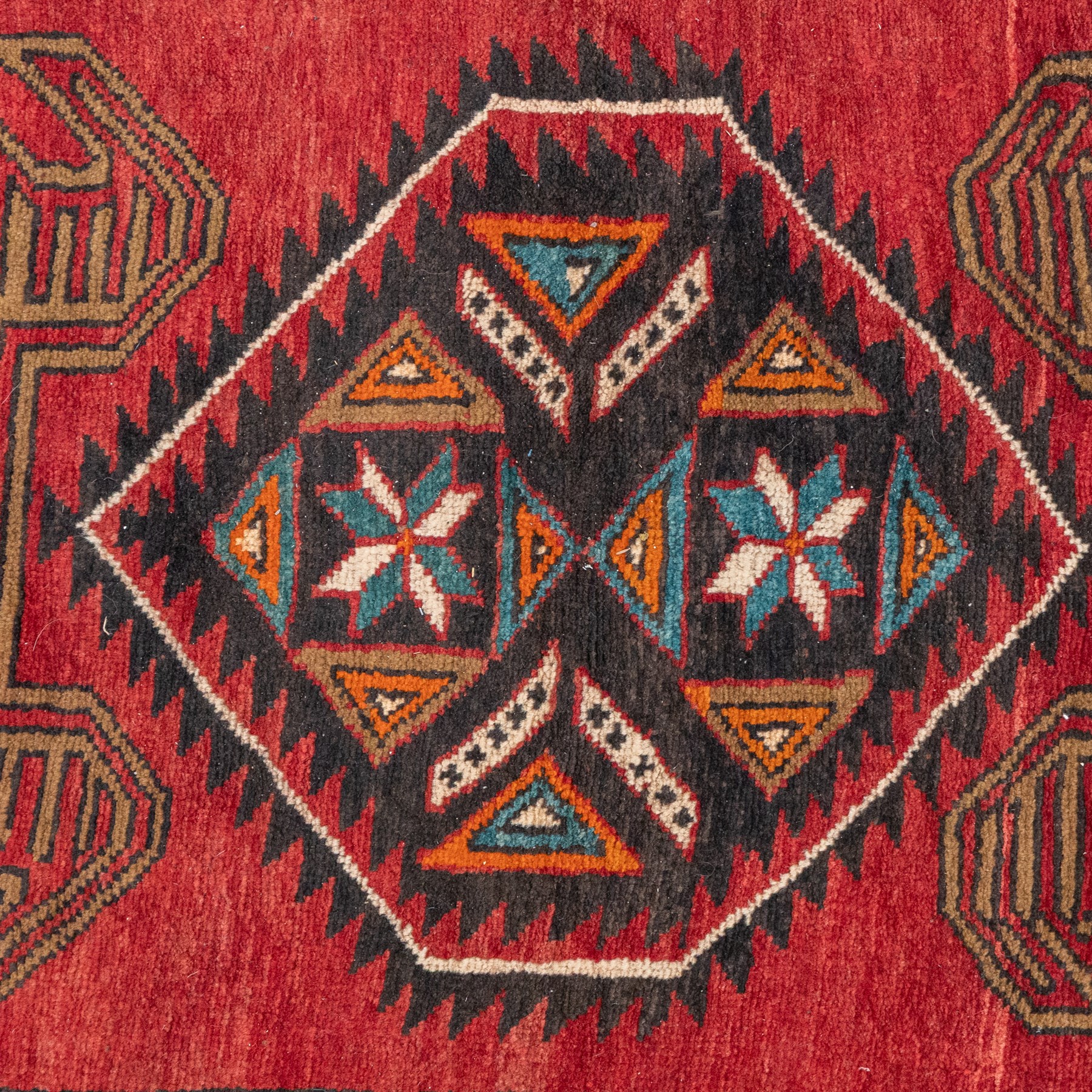 North East Persian Kurdie runner, the red field decorated with three serrated diamond medallions alternating with four ochre hooked motifs enclosing polychrome cruciform panels, within multiple geometric borders of repeating triangles and diamond devices