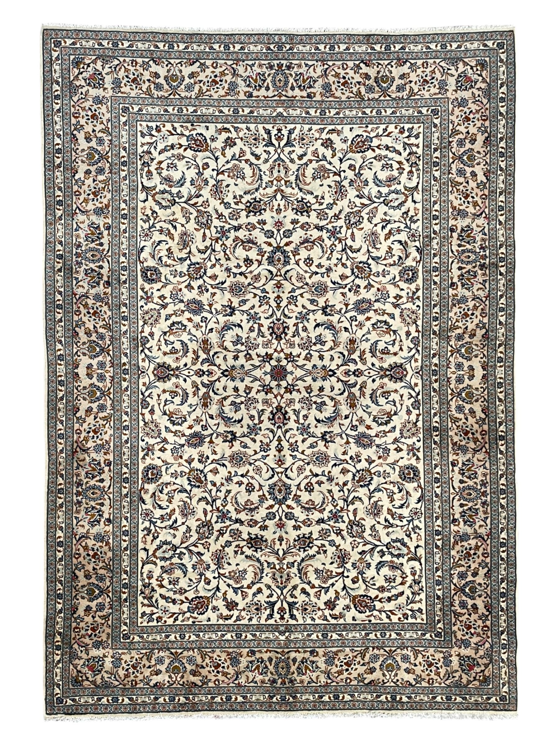 Persian Kashan ivory ground rug, decorated with curled leafy branches and palmettes, the border with scrolling design decorated with further palmettes, within floral pattern guard stripes