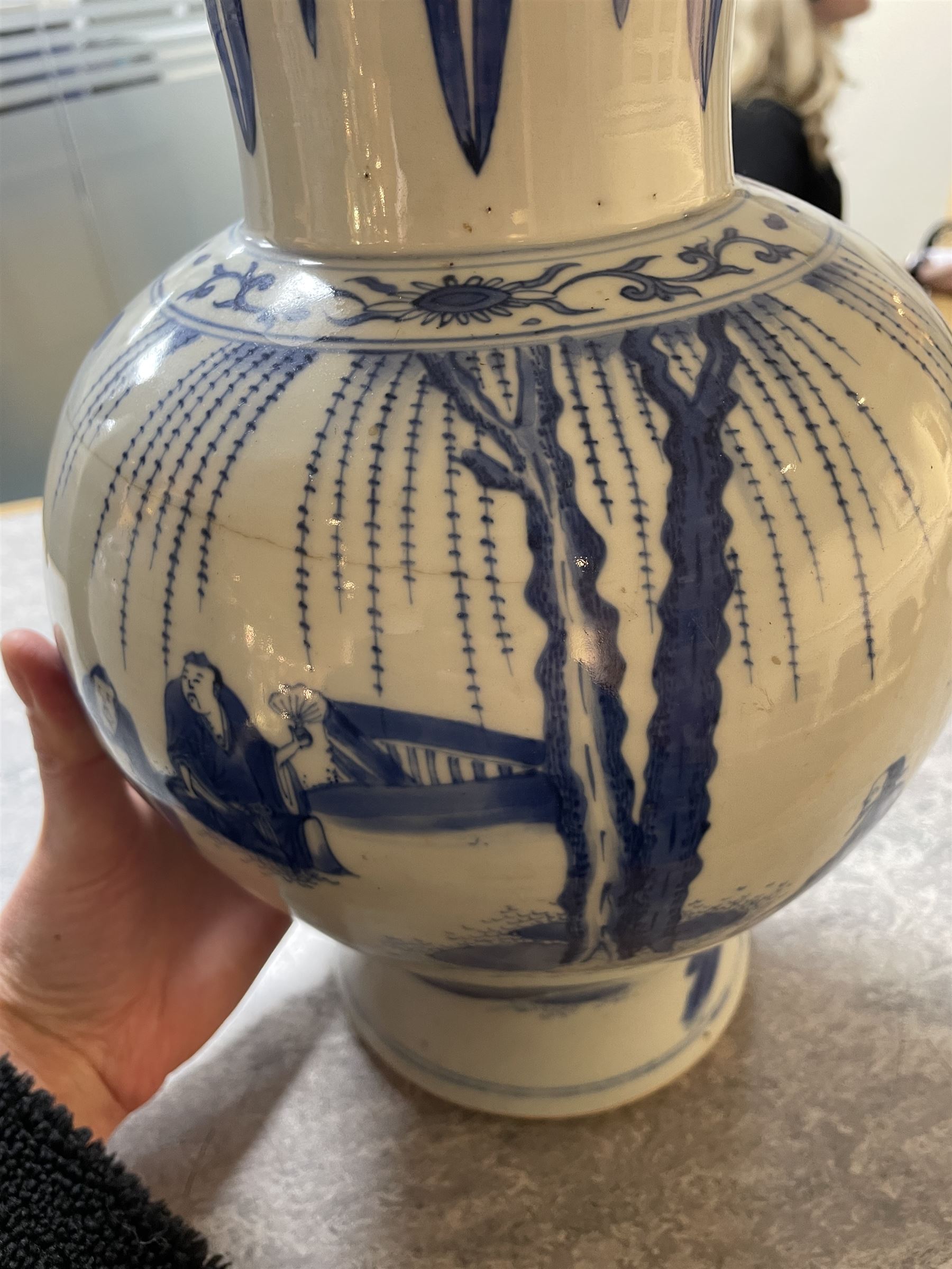 Pair of Chinese Kangxi blue and white porcelain vases, each of baluster form, painted with an outdoor scene containing figures seated upon the ground reading scrolls and holding fans, willow and bamboo tress, rock work and water, H27cm