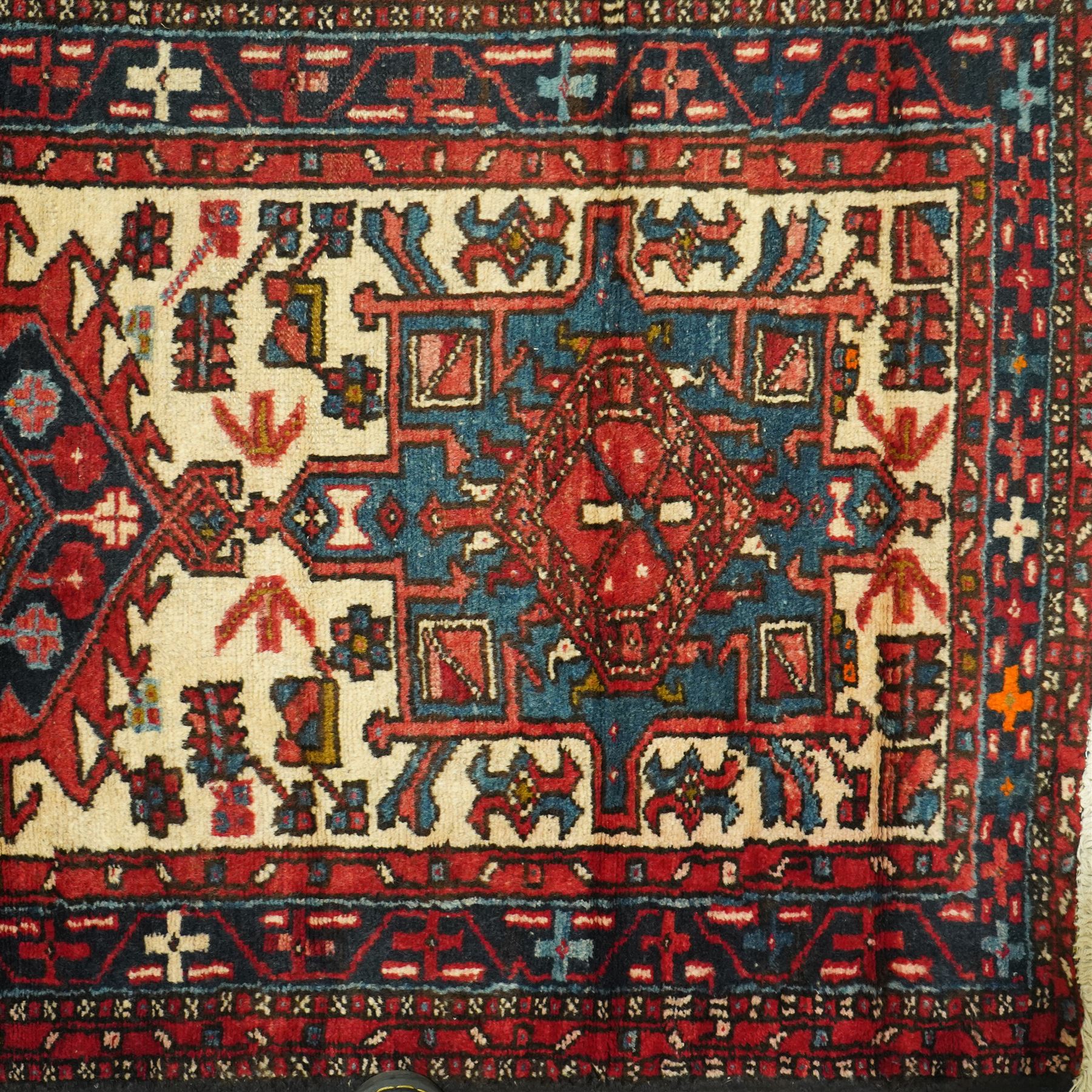 Caucasian Shirvan hand-knotted runner, ivory field decorated with a vertical sequence of bold hexagonal and lozenge medallions, each enclosing stylized geometric motifs, flanked by angular floral latch-hook devices, field dominated by madder red  and ivory with subsidiary colours of indigo, brown, and turquoise, with fringe ends   