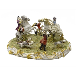  Capodimonte porcelain model depicting an 18th century hunting group, a man and woman seated upon rearing horses surrounded by huntsmen and hounds on naturalistic base with shaped scroll border, signed G. Cuman, L53cm   