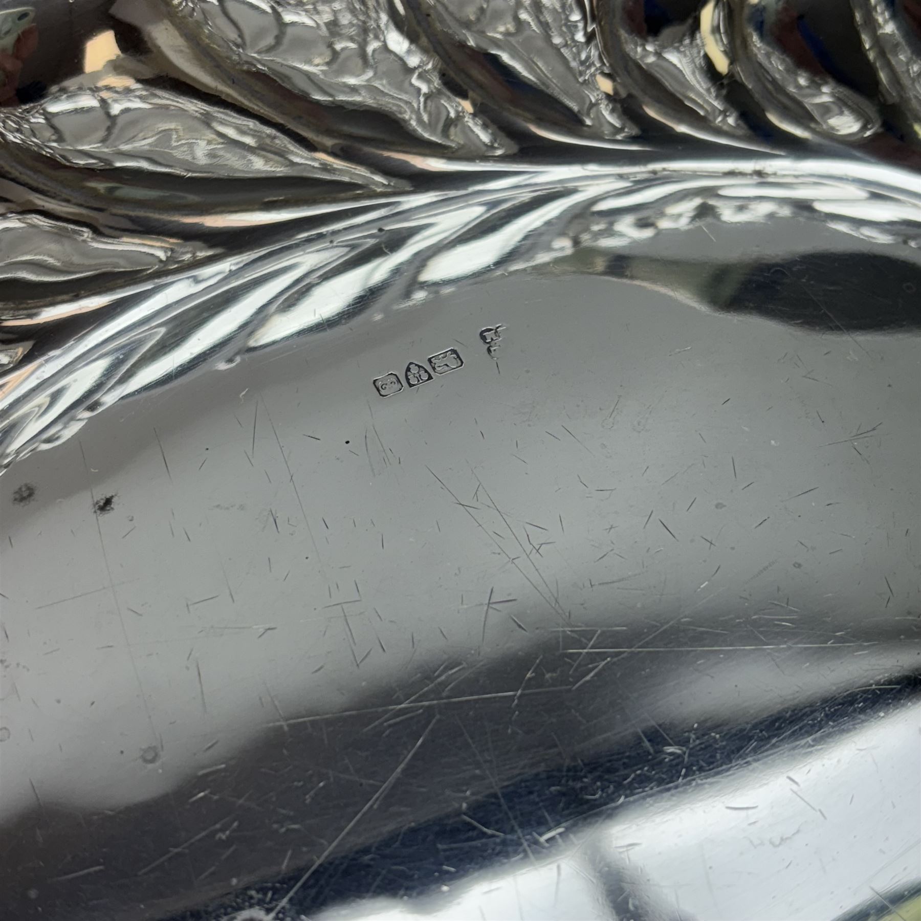 Edwardian silver swing handled basket, of oval form with shaped rim, embossed with floral decoration and with pierced latticework sides, upon four pad feet, hallmarked Chester 1905, maker's mark worn and indistinct