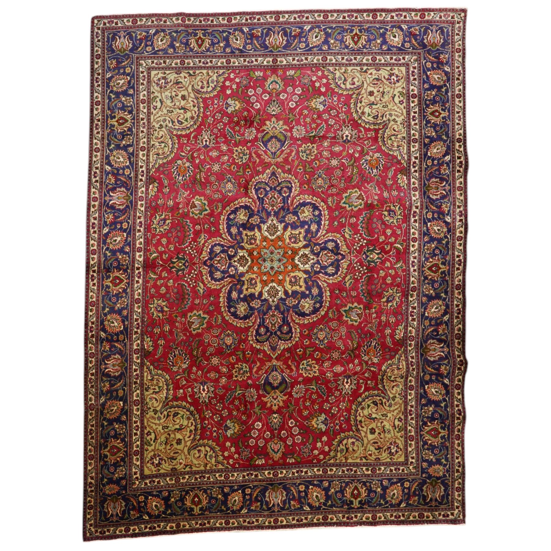 North East Persian Meshad hand-knotted carpet, crimson field with central lobed medallion in tones of indigo, ivory and soft blue, with an all-over arrangement of scrolling vinery, palmettes, and floral  sprays, conforming spandrels, main border of stylized floral vinery framed by multiple guard borders, with cotton fringe ends
