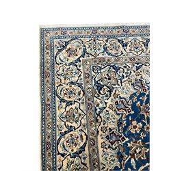 Persian Kashan blue ground rug, central floral rosette medallion within a field of swirling branches and palmettes, the border with trailing pattern interspersed with stylised plant motifs