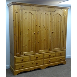  Solid pine triple wardrobe, projecting cornice, three doors enclosing hanging rails above four short and two long drawers, shaped plinth base, W207cm, H208cm, D56cm  