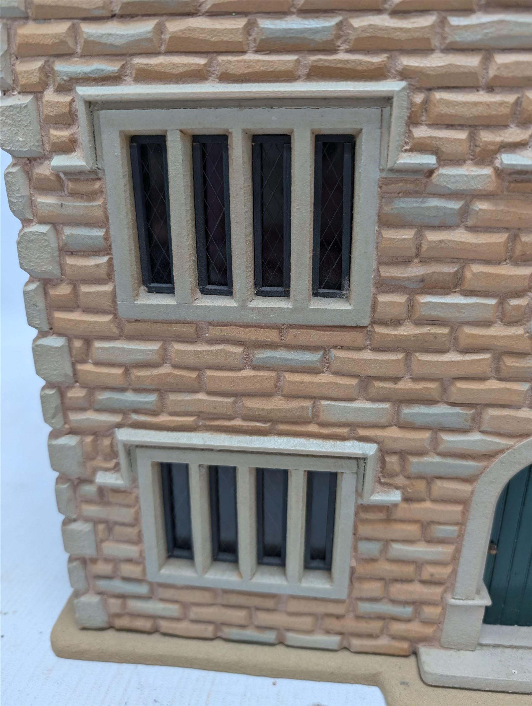 1:24 scale stone effect three-storey cottage dolls house, with green arched door and lattice effect windows, decorated to the interior with wooden floors, wired lighting and fire places, H45cm, W57cm, D26cm