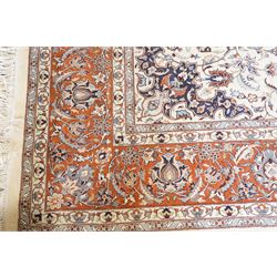 Persian ivory ground Kashan carpet, the busy field decorated with a central floral pole medallion with matching spandrels, the field profusely decorated with scrolling foliate motifs, the crimson guard stripe with repeating scrolling palmettes