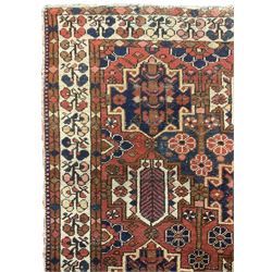 Persian crimson ground rug, the field decorated with three rows of stylised plant medallions and small flowerhead motifs, repeating floral design border with guards 