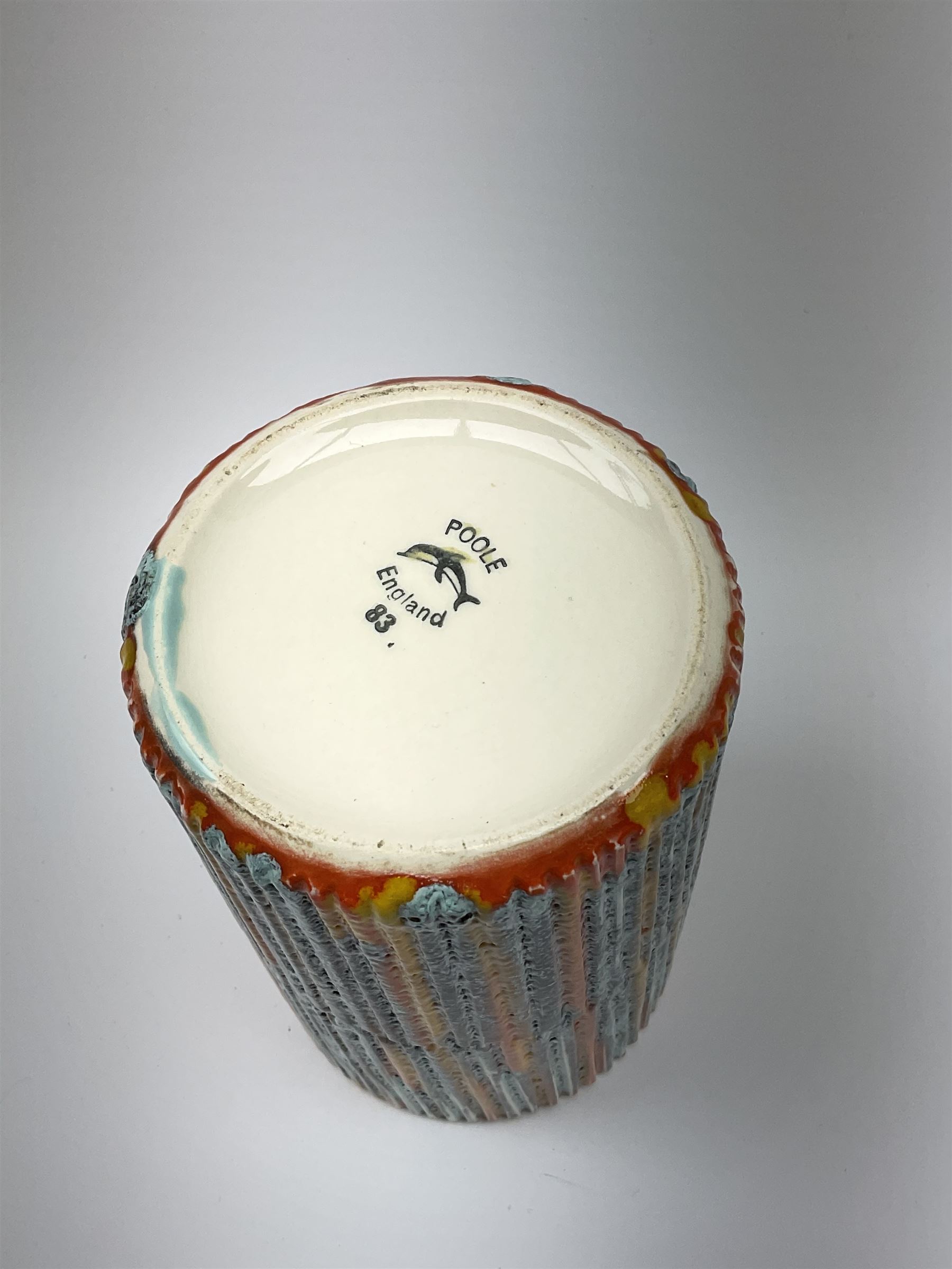 A Poole Pottery Delphis vase, shape 83, with textured effect in merging tones of red, yellow and blue, with printed mark beneath, H15cm.
