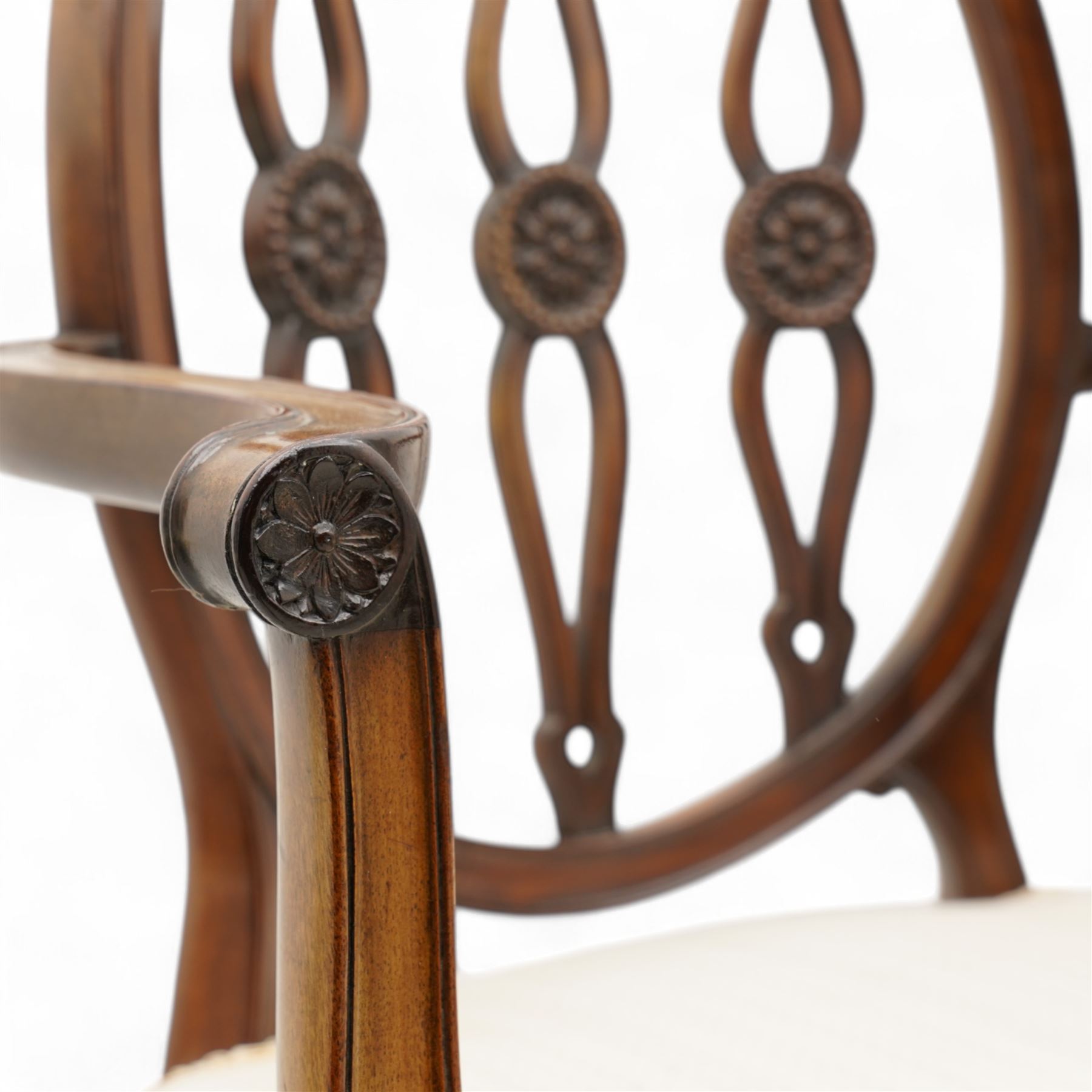 Set of six (4+2) late 19th to early 20th century Hepplewhite design mahogany dining chairs, moulded oval framed back with three shaped and pierced upright rails decorated with floral carved roundels, upholstered in pale fabric, on square tapering supports with recessed panels and block feet 