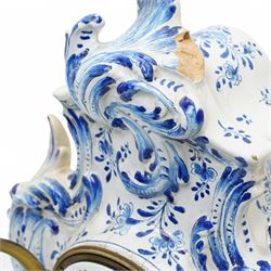 19th century delft blue and white Rococo style 8-day mantle clock, with a scrolling case and floral decoration, depiction of a courting couple in 18th century dress to the front and a contrasting scene of sailing ships on a lake to the rear, with a late 19th-century French twin train movement, enamel dial with Roman numerals, five minute Arabic's and gilt Louis XVI hands within a glazed cast bezel, with a rack striking movement sounding the hours and half-hours on a bell. No pendulum or key.  