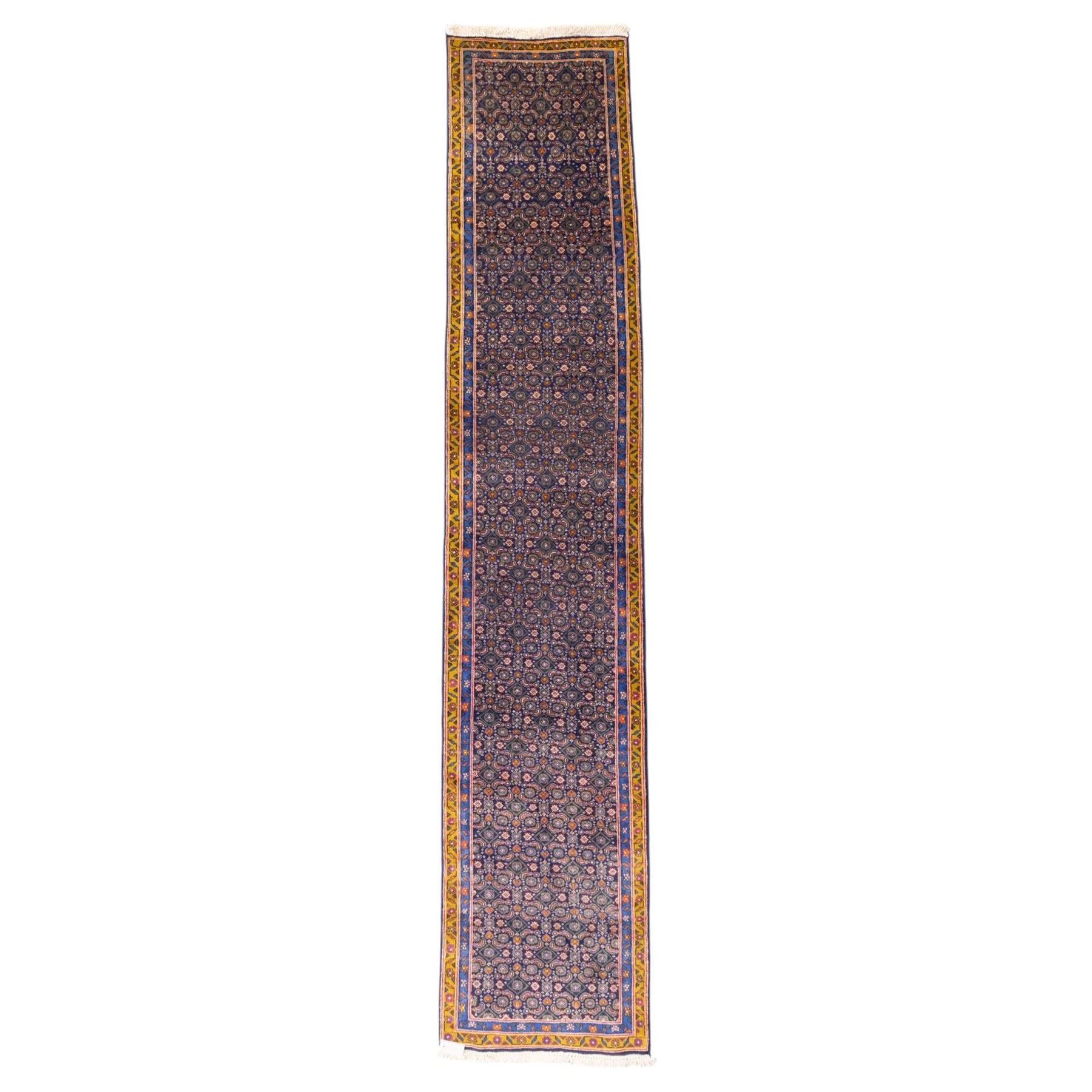 North West Persian Bidjar hand-knotted runner, decorated with an all-over herati pattern on a deep indigo ground, the field is filled with a repeating diamond and rosette motifs, interspersed with stylized leaves and floral elements, framed by a border on an ochre ground flanked by contrasting guard borders, with cotton fringe ends 