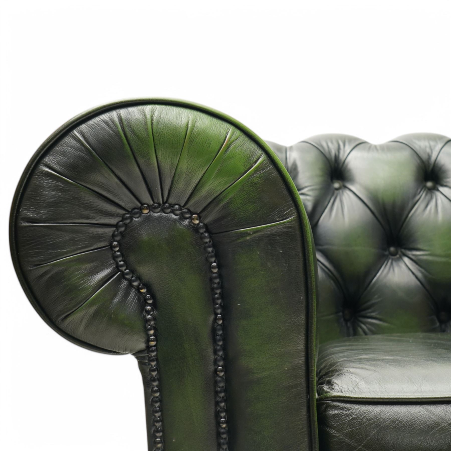 Thomas Lloyd - two-seat hardwood-frame Chesterfield sofa, traditional rolled back and arms upholstered in deeply buttoned green leather, on turned bun feet 