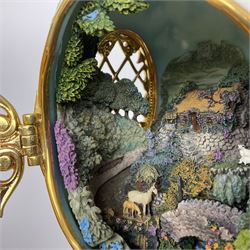 Franklin Mint The Emerald Isle Collector Egg, the egg decorated with embossed shamrocks upon a cream ground, with a gilded shamrock finial, accents and openwork door, opening to reveal a miniature landscape scene, upon three gilded feet set with green paste stones, with certificate of authenticity H23cm, 
