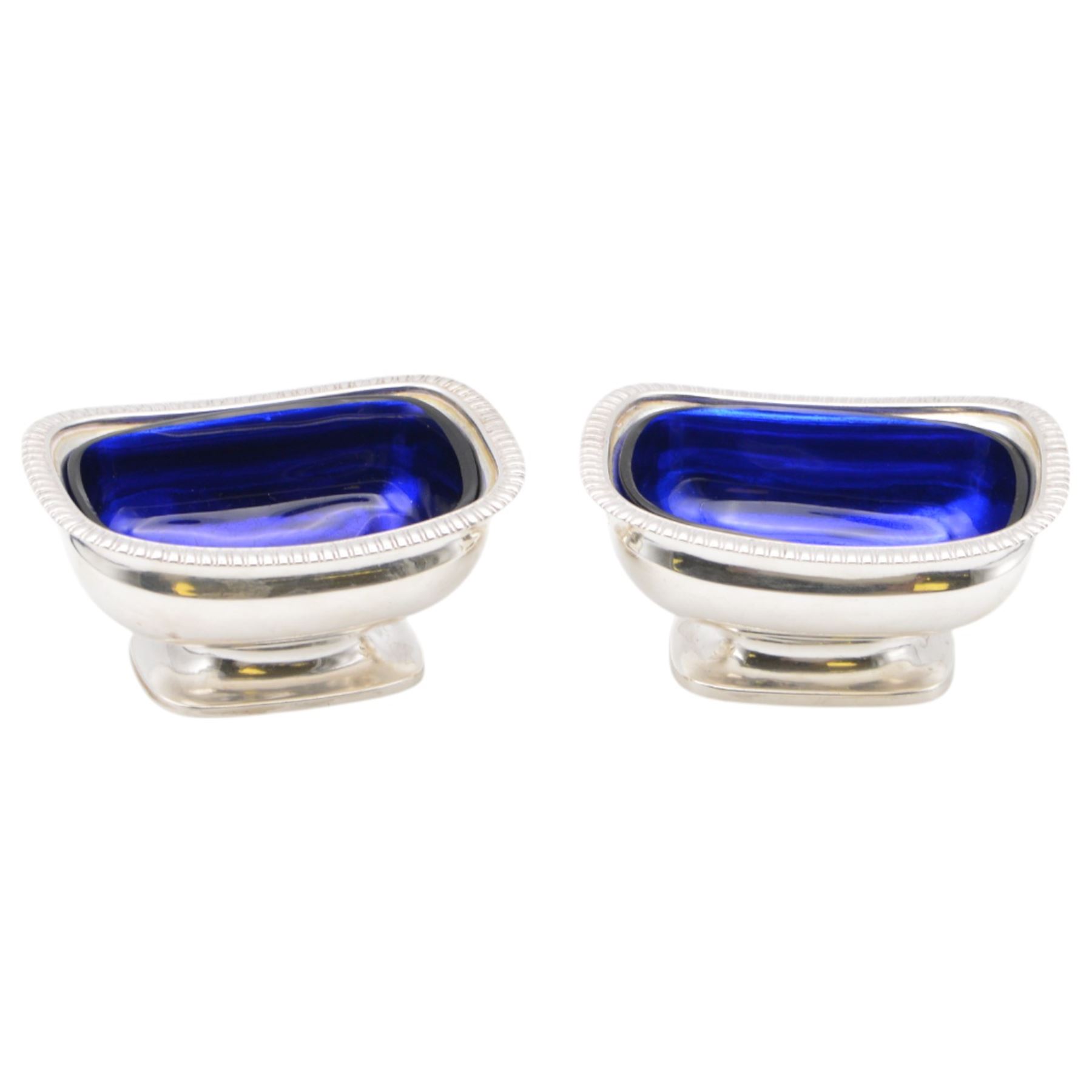 Pair of George III silver open salts, of rectangular form with gadrooned rim and upon a rectangular base, hallmarked J E Terrey & Co, London 1818, with blue glass liners, H4.5cm