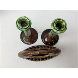 Linthorpe pottery vase with crimped rim and ovoid body, Linthorpe jug with high loop handle and crimped spout, a pair of candlesticks with a green, brown glaze and other similar pottery 