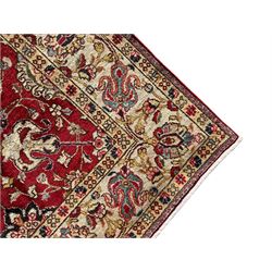 Persian Tabriz crimson ground rug, the field decorated with large palmette and stylised plant motifs connected by interlaced leafy branches, trailing border decorated with similar palmette motifs within floral pattern guard stripes, with signature panel 