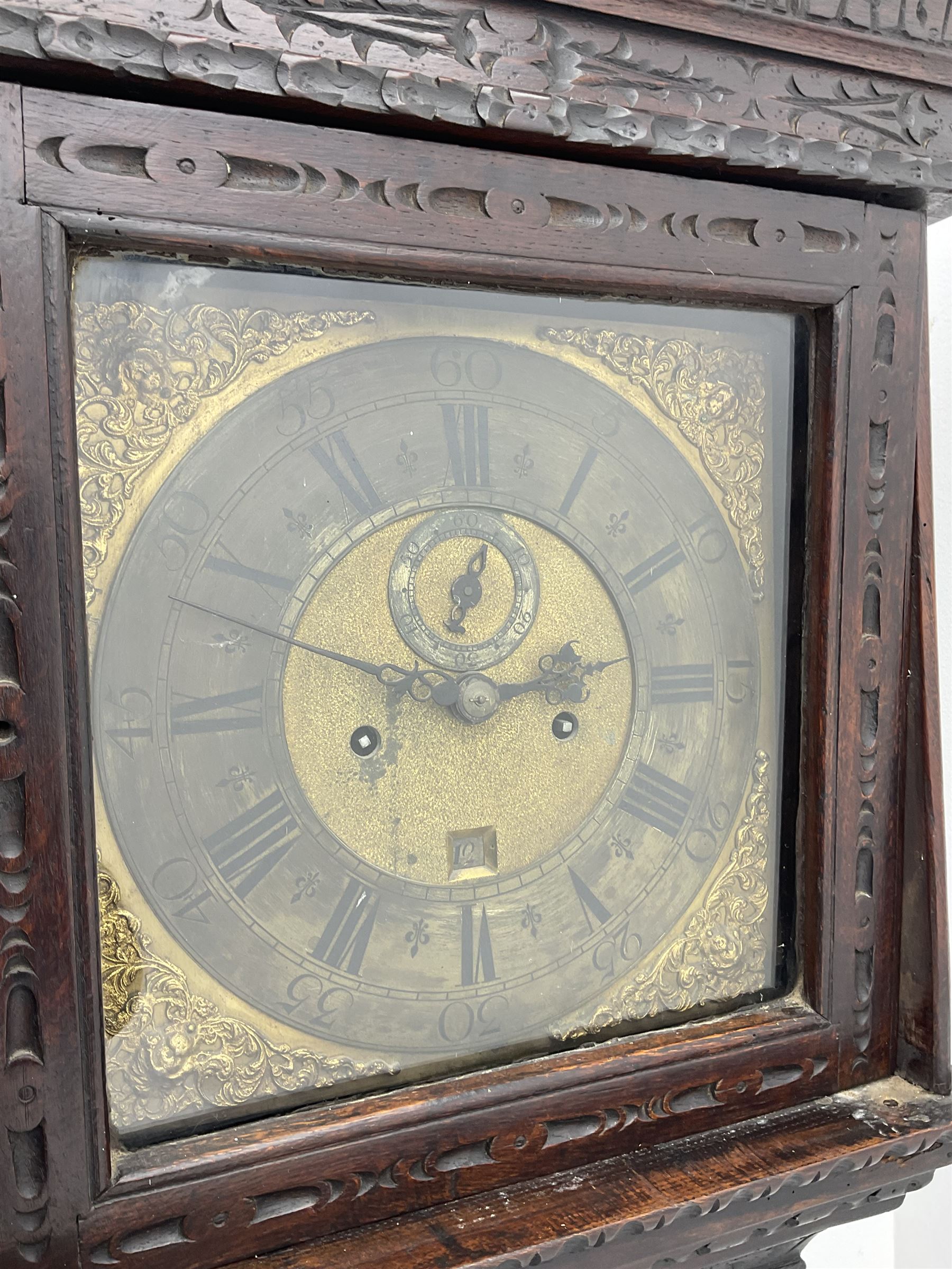18th century oak longcase clock with later carving, the hood with projecting cornice over square glazed door, trunk door carved with tree of life, foliage carved base, on ogee bracket feet, brass dial with Roman chapter ring and subsidiary seconds and calendar aperture, ornate mask cast spandrels, twin train driven movement striking on bell 