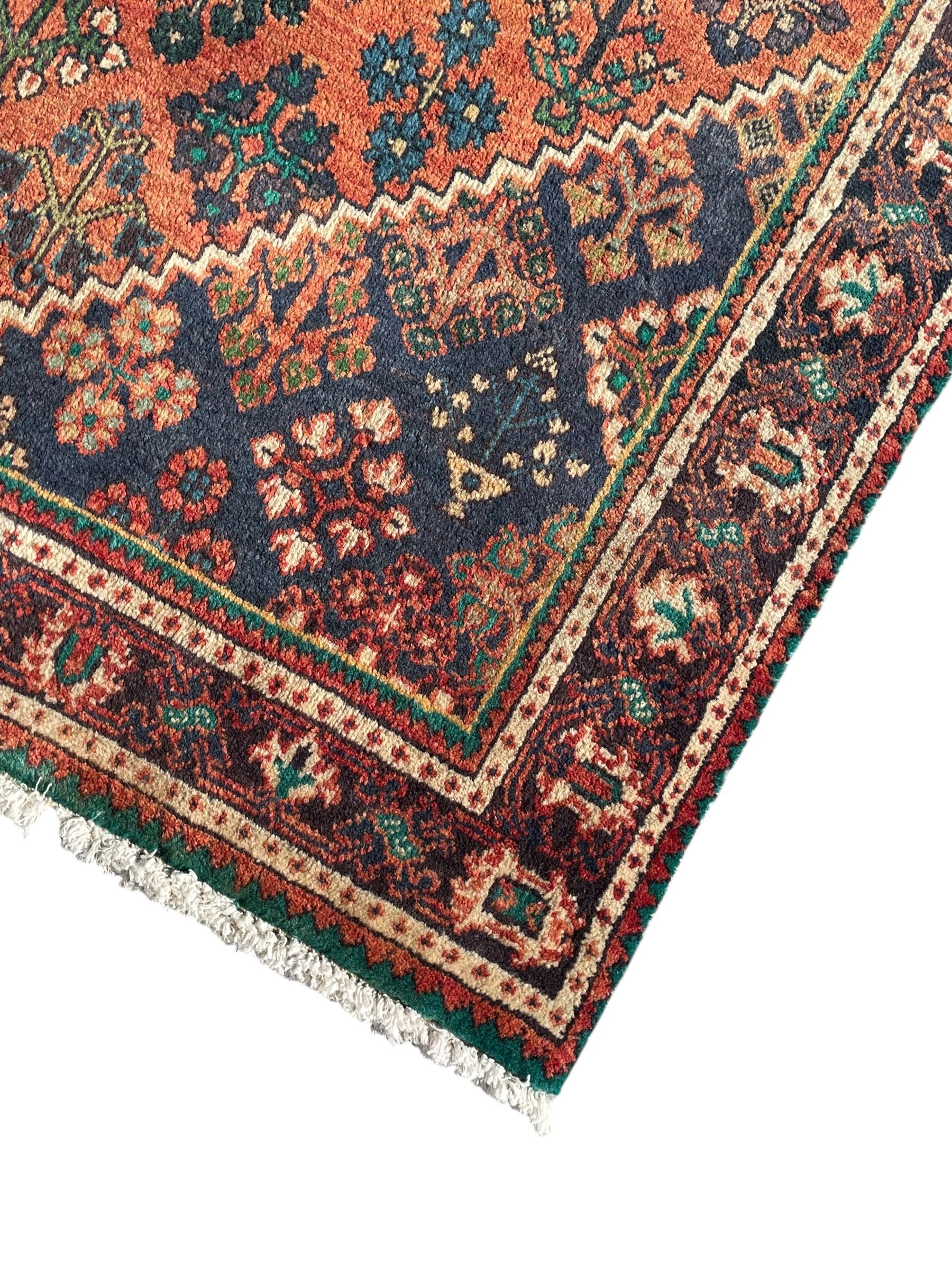 Persian Joshaghan rust ground rug, stepped lozenge medallion surrounded by repeating foliate lozenge motifs, the border decorated with stylised plant motifs, within geometric guard stripes
