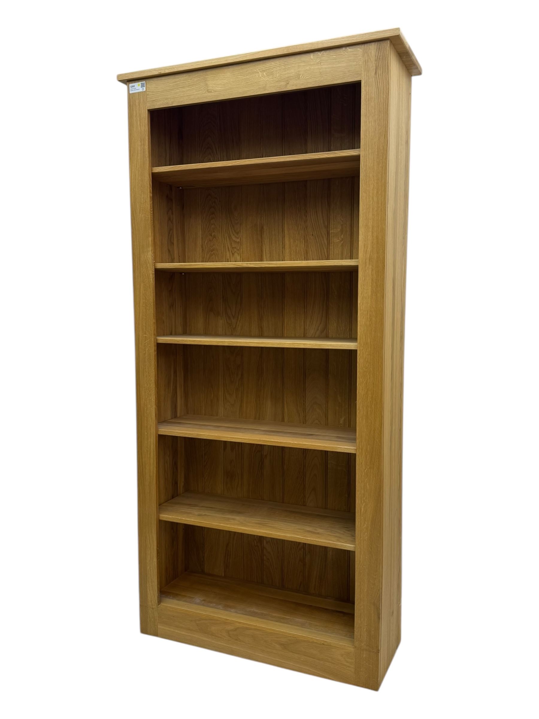 Contemporary light oak open bookcase, rectangular form with projecting top, fitted with five adjustable shelves, on a straight plinth base