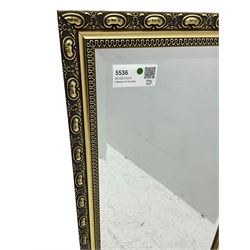 Gilt framed wall mirror, rectangular bevelled mirror plate enclosed by gilt-edged border with continuous wave pattern, outer border with oval medallions and foliate designs