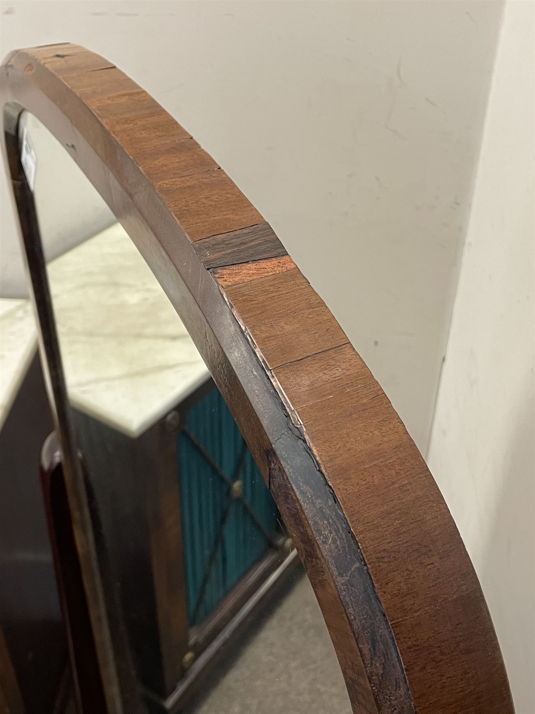 Early 19th century mahogany cheval dressing mirror, plain mirror plate within chamfered frame with arched top, on rolled horns and out-splayed rolled feet, united by turned stretcher 