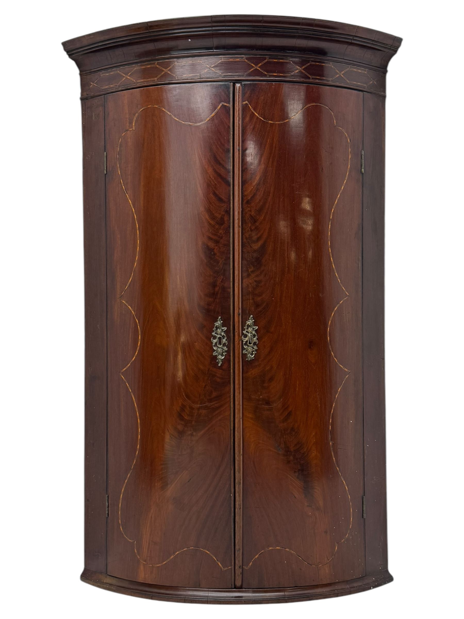Late Georgian mahogany hanging corner cupboard, moulded cornice with interlaced boxwood stringing pattern above two cupboard doors inlaid with wave form boxwood stringing and four internal shelves 