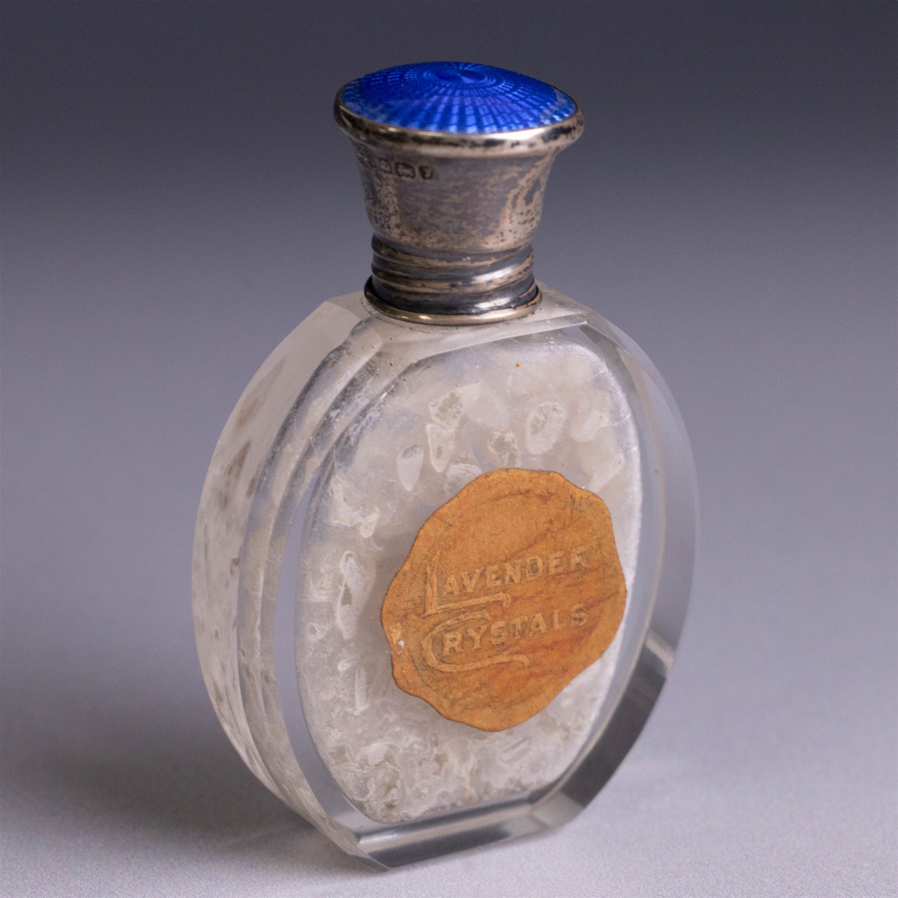 Three silver topped scent bottles, comprising cut glass example with pink guilloche enamel cover, oval example with blue guilloche enamel cover and one other, all hallmarked, largest H6.5cm