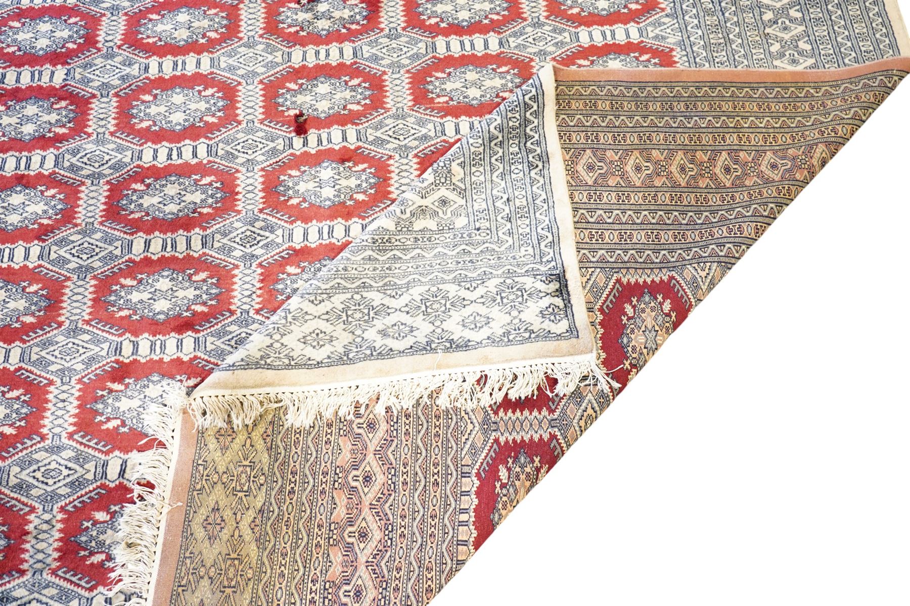Jaldar Bokhara crimson and pale ground carpet, the field decorated with five rows of Gul motifs, within intricate multi-band border decorated with repeating geometric designs 