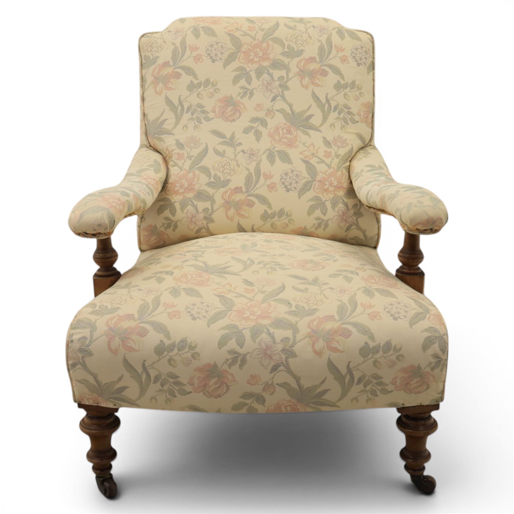 Victorian mahogany framed deep seat low drawing room chair, upholstered in beige floral fabric, on turned supports terminating in castors