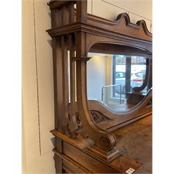 Late 19th century Arts & Crafts period oak mirror back sideboard, shaped bevelled mirror back carved with foliate scrolls and flower heads, down swept supports with elongated club-shaped uprights, moulded rectangular top over two drawers and three cupboards, the drawer fronts with copper handles decorated with sailing ships, panelled doors carved with mythical beasts, flowerheads and foliage, on moulded block feet