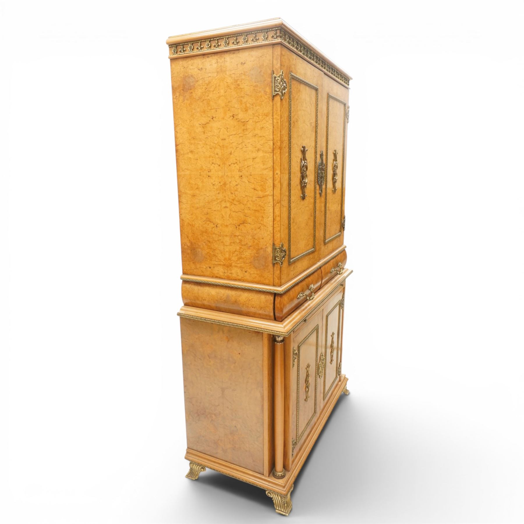 Early 20th century Art Deco burr maple mirrored drinks cabinet, rectangular top with gilted cornice, twin cabinet doors with gilt escutcheons, enclosing a mirrored interior with shelves behind the doors, marble base to the top section above two short drawers over a marble inset slide, the lower cabinet with cabinet doors flanked by pilasters, raised on gilted bracket feet 