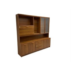 Mid-20th century teak wall unit, fitted with two glass shelves flanked by two glazed cupboard doors and fall-front cupboard, base fitted with three drawers flanked by two double cupboards