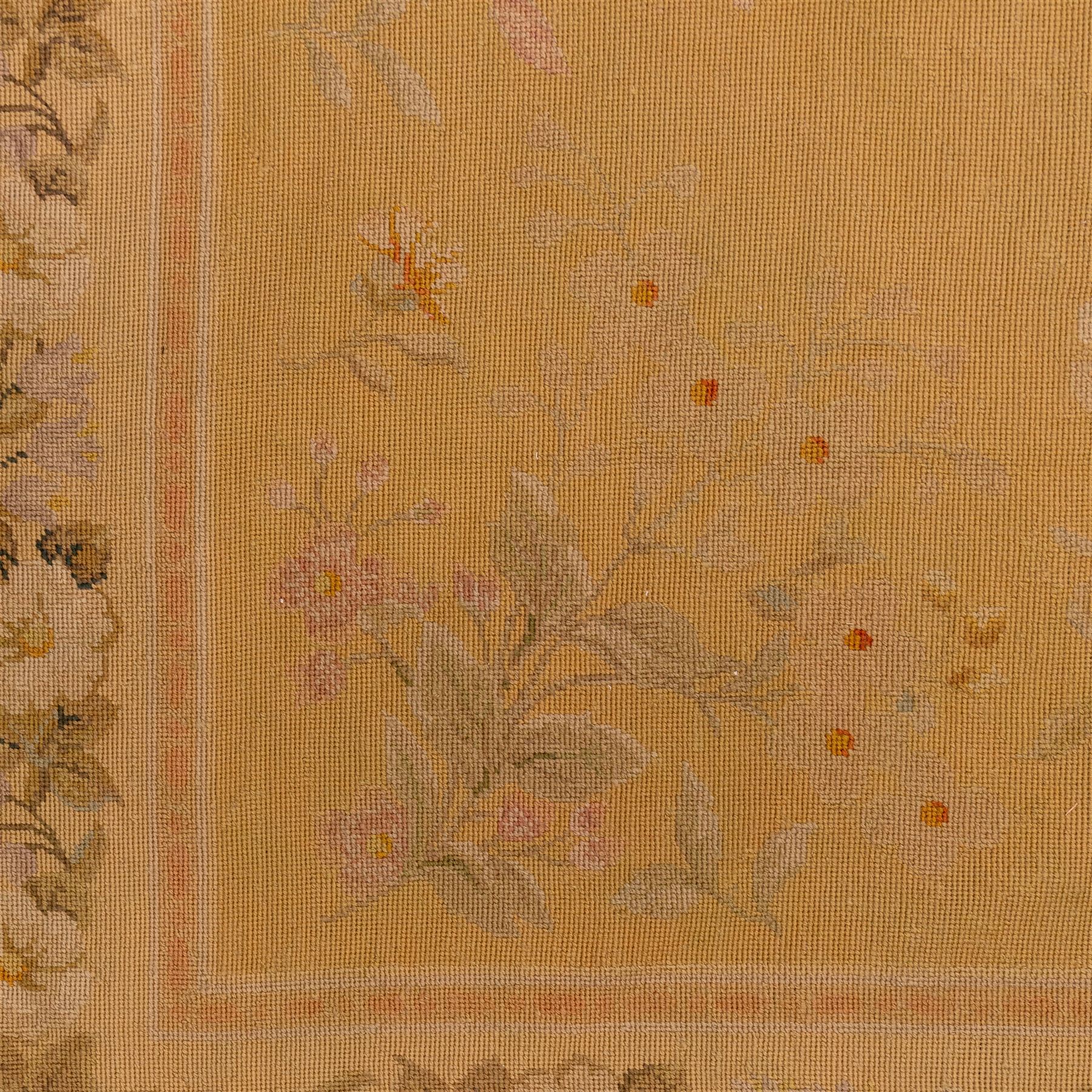 20th-century Aubusson-style woven tapestry of rectangular form with mustard yellow field decorated with scattered floral sprays in soft pastel tones of pink, cream, and muted green, within a narrow guard stripe with an outer border of trailing blossoms and foliage 