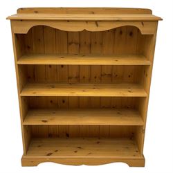 Pine open bookcase, raised back over moulded top and shaped frieze rail, fitted with three shelves, on shaped plinth base